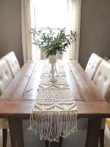 Detailed Macramé weave of an off-white cotton table runner with fringe and geometric patterns