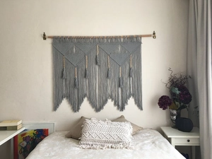 Detail of grey handmade bohemian macrame wall hanging with geometric weave and long tassels