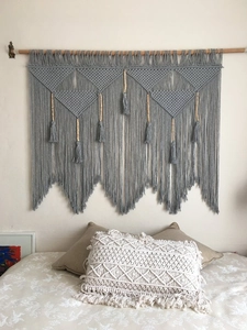 Detail of handcrafted bohemian wall hanging with tassels and boho woven cushion cover