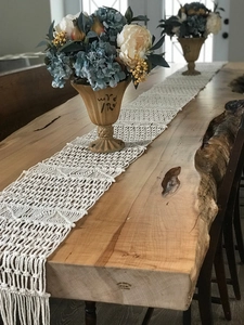 Detail view of handmade bohemian table runner with tassels on a live edge wooden dining table