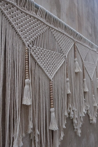 Detailed close-up of Bohemian wall tapestry with intricate knots and wooden beads