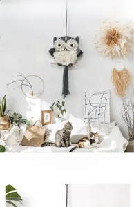 Detailed close-up of handmade woven owl tapestry with cotton tassels and wooden rod