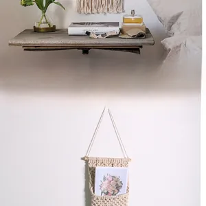 Detail of bohemian handmade woven cotton rope wall hanging storage pocket with wooden rod