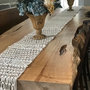 Handmade boho cotton woven table runner with decorative tassels on a wooden dining table