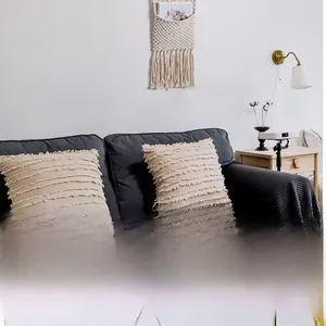 Close-up of beige bohemian throw pillows with layered fringe on a grey sofa