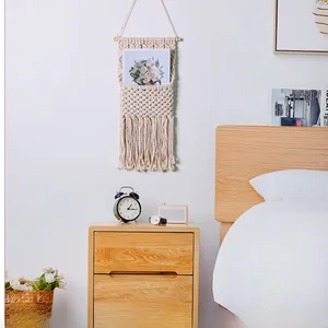Close-up of handmade macramé wall pocket in boho style with tassels and wooden rod