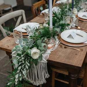 Handmade cream macrame table runner with long tassels on a dark wood dining table