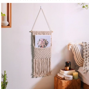 Detail of bohemian handmade woven cotton wall pocket hanging with wooden rod and tassels
