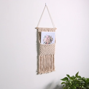 Handwoven bohemian wall hanging magazine rack made of white cotton rope with tassels