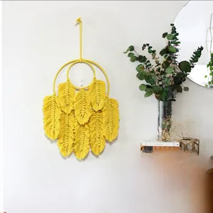 Détail de tapisserie en plumes tissées main jaune avec texture bohème sur mur blanc