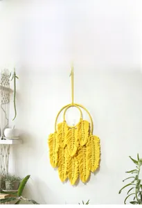 Détail du macramé mural jaune avec franges en forme de plumes pour décor bohème