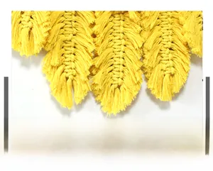 Détail de suspension murale en macramé jaune faite main avec franges en forme de plumes