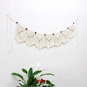 Close-up of handmade macrame tapestry fringe with cotton ropes and brown wooden beads