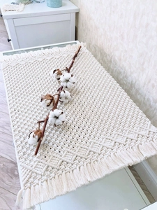 Detailed close-up of handmade cream cotton woven table runner with diamond patterns and tassels