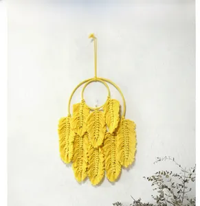 Détail d'une suspension murale en macramé jaune avec des motifs de plumes faits à la main