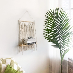 Detail of bohemian handmade macrame wall shelf with natural wood board and cotton fringe