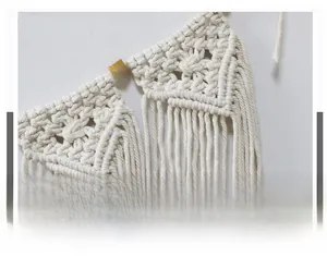 Detail of hand-woven beige cotton rope macrame with tassels and gold geometric bead