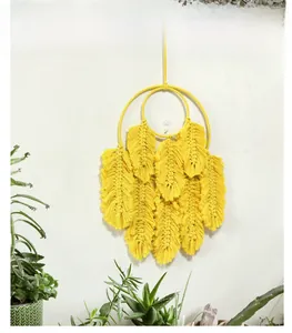 Détail de la décoration murale bohème en coton tressé jaune avec feuilles à franges