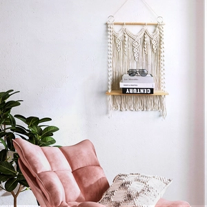 Detail of bohemian handmade macrame wall shelf with beige cotton rope and light wood plank