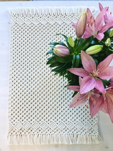 Detail of handmade macramé table runner featuring cream cotton weave and bohemian tassels