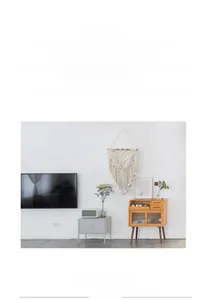 Detailed view of hand-woven Bohemian cotton tapestry with long tassels on wooden rod