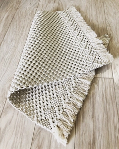 Close-up of bohemian macrame table runner with hand-woven cream cotton ropes and tassels