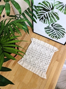 Detail of hand-woven beige cotton table runner featuring bohemian tassels and fringe