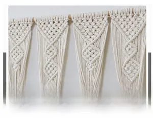 Close-up of handmade cotton rope macrame wall hanging with geometric weave on a wooden pole