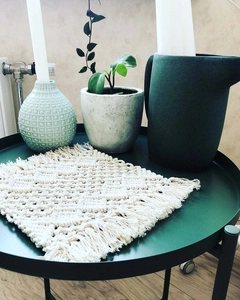 Macro detail of hand-woven beige cotton placemat featuring fringe trim and geometric texture
