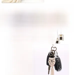 Detail view of a beige handmade macrame keychain on a black car key with lobster clasp