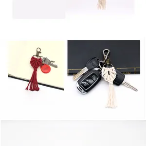Detail of handmade bohemian woven keychain with red and cream tassels and metal clasp