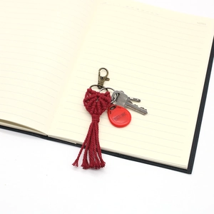 Detailed macro view of handmade burgundy woven heart keychain with cotton tassels and clip