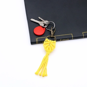 Close-up of handmade yellow macrame leaf keychain with fringe and antique bronze clasp