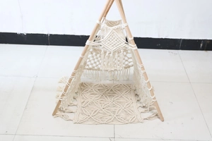 Detail of bohemian handmade cotton rope macrame pet tent with natural wooden poles