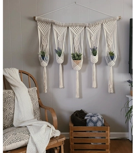 Detail of bohemian macrame wall hanging with five pockets and lush artificial greenery