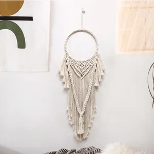 Dettaglio di decorazione murale boho in cotone bianco intrecciato a mano con lunghe nappe