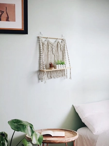 Detailed close-up of bohemian hand-woven cotton macrame wall shelf with natural wood tray