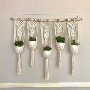 Handmade macrame wall hanging with 5 plant holders and wooden rod in boho style