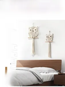 Detailed close-up of two handmade bohemian macrame owl wall hangings on a white wall