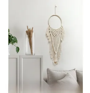 Dettaglio di un arazzo macramè bohémien con trama geometrica e lunghe frange in corda di cotone