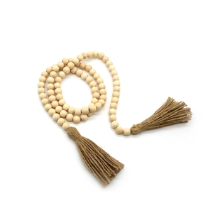 Détail d'une guirlande en perles de bois naturel avec des glands en jute marron
