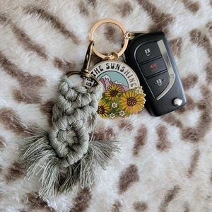 Detail of bohemian cotton rope keychain with sunflower enamel tag and lobster clasp