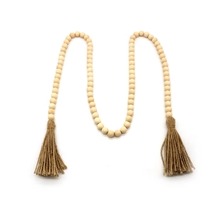 Détail d'une guirlande en perles de bois naturel avec pompons en corde de jute sur fond blanc