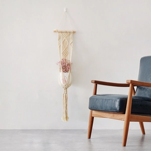Handwoven macrame plant hanger with wooden rod and tassel detail for bohemian wall decor