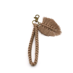 Detail of handmade bohemian woven keychain featuring fringe leaf and vintage metal clasp