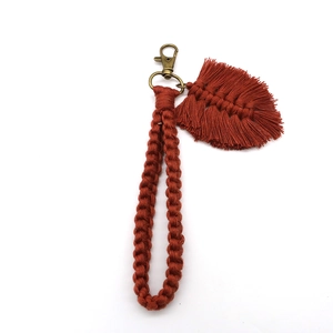 Macro shot of rust red handmade bohemian woven keychain with feather leaf fringe