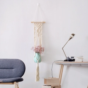Detail of bohemian hand-woven macrame plant hanger with pink dried flowers and ceramic vase
