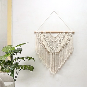 Handmade Bohemian macrame wall hanging with geometric patterns and fringe on white wall