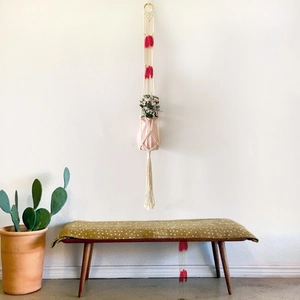 Detail of bohemian handwoven cotton plant hanger with pink tassels and a ceramic vase