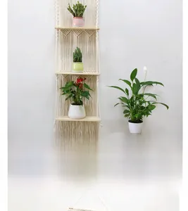 Detail of a 3-tier boho macrame floating shelf with wooden boards and white cotton tassels